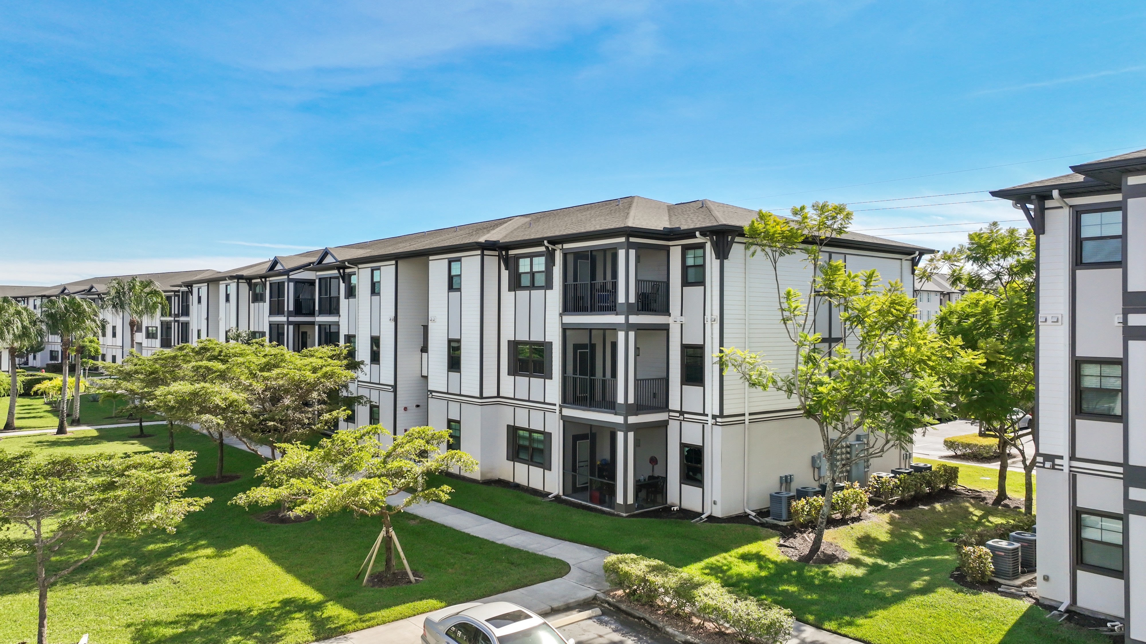 A row of modern townhouses with green lawns in front.